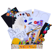 Load image into Gallery viewer, A children's outer space craft kit displayed in a decorative box, filled with printed templates, stickers, paint pots, glitter, scissors, and other craft supplies on a white background.